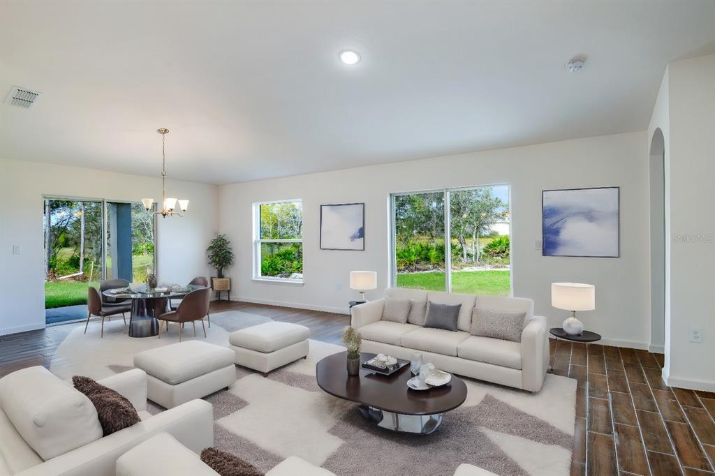 A bright living and dining area features white furniture, a dark coffee table, and tile flooring — 179 AURELIA COURT, KISSIMMEE, FL