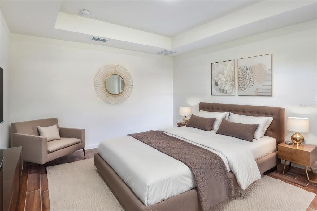 A bedroom features a brown upholstered bed, a matching armchair, and a circular wall mirror — 179 AURELIA COURT, KISSIMMEE, FL