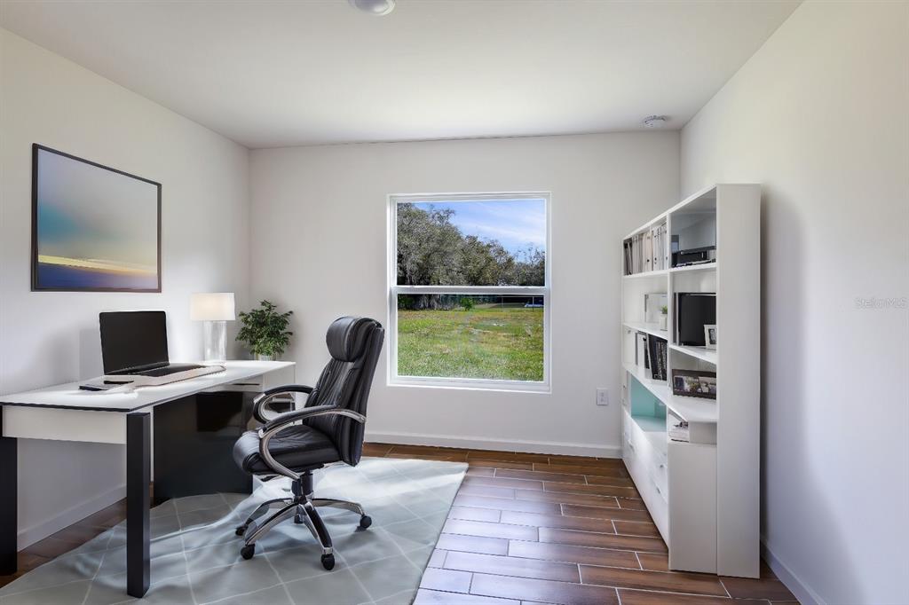 A home office with a desk, black chair, white bookshelf, and a window overlooking grass — 179 AURELIA COURT, KISSIMMEE, FL