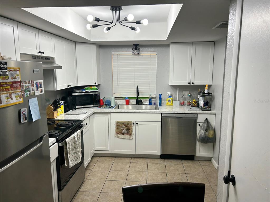A kitchen with white cabinets, stainless steel appliances, and a modern light fixture — 6301 58TH STREET N UNIT 506, PINELLAS PARK, FL