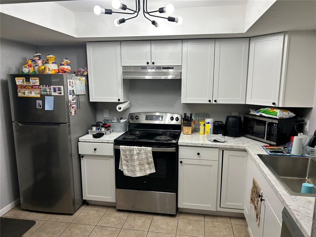 A kitchen features white cabinets, stainless steel appliances, and a marble-patterned countertop — 6301 58TH STREET N UNIT 506, PINELLAS PARK, FL