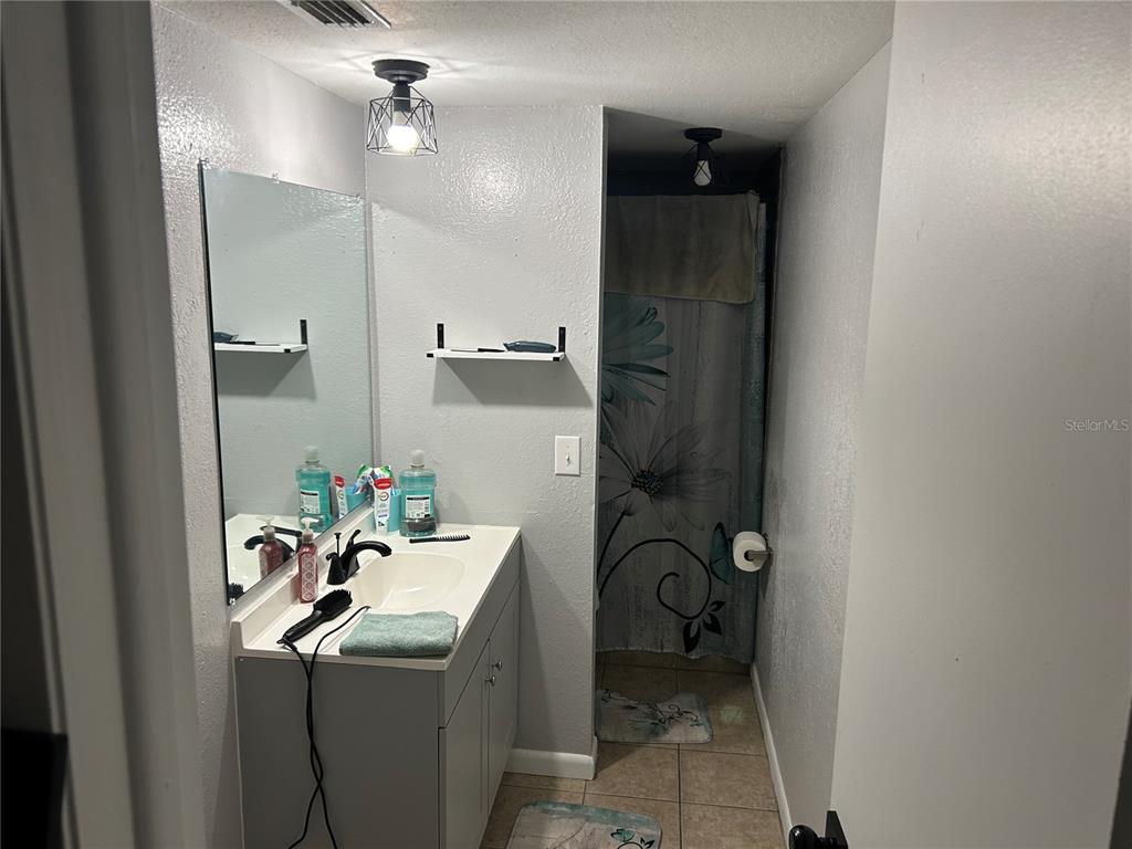 A bathroom features a vanity with a mirror, a sink, and a shower with a curtain — 6301 58TH STREET N UNIT 506, PINELLAS PARK, FL