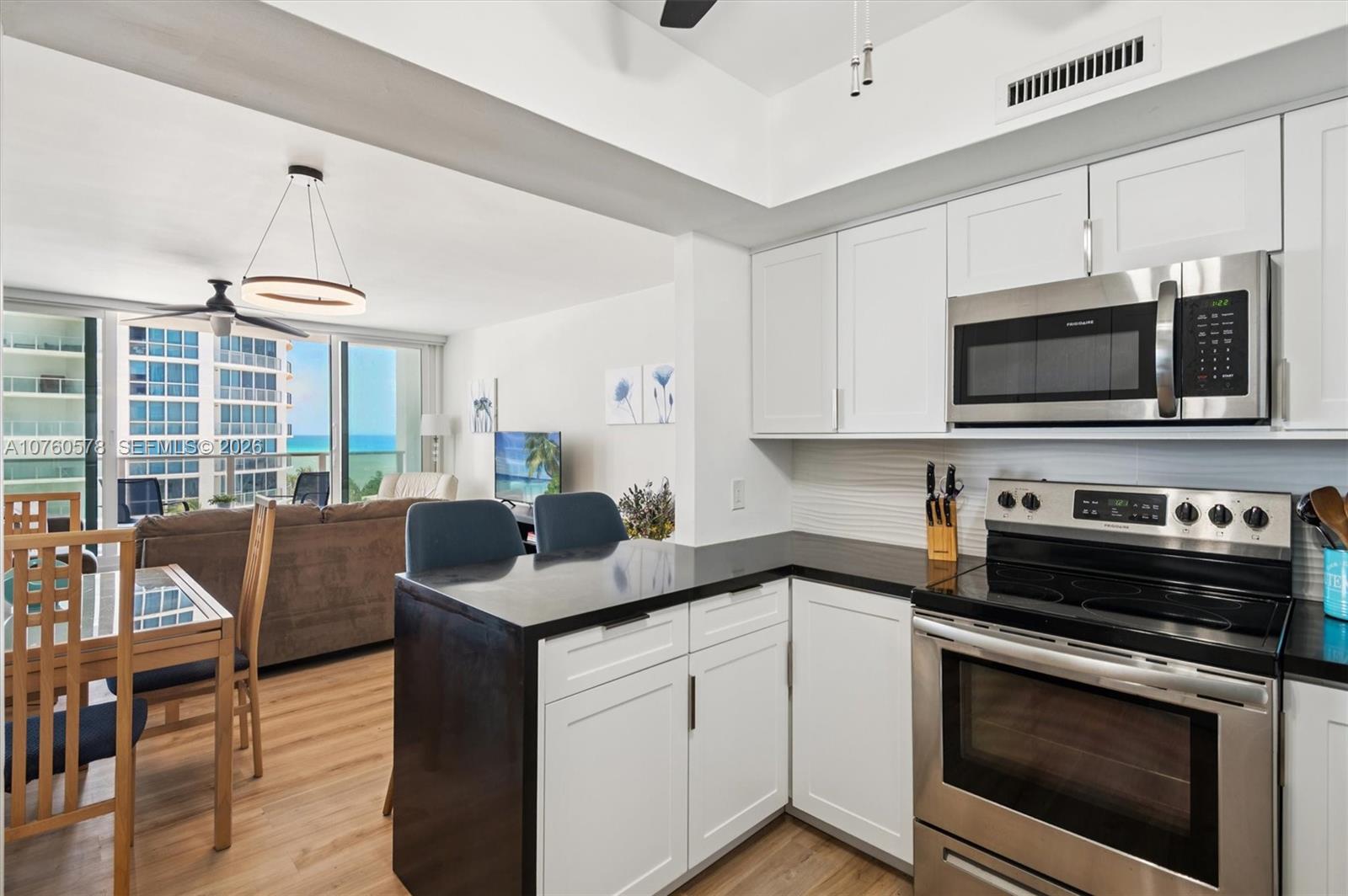A kitchen with white cabinets and black countertops overlooks a living area with ocean views — 3505 S Ocean Dr # 710, Hollywood FL 33019, HOLLYWOOD, FL