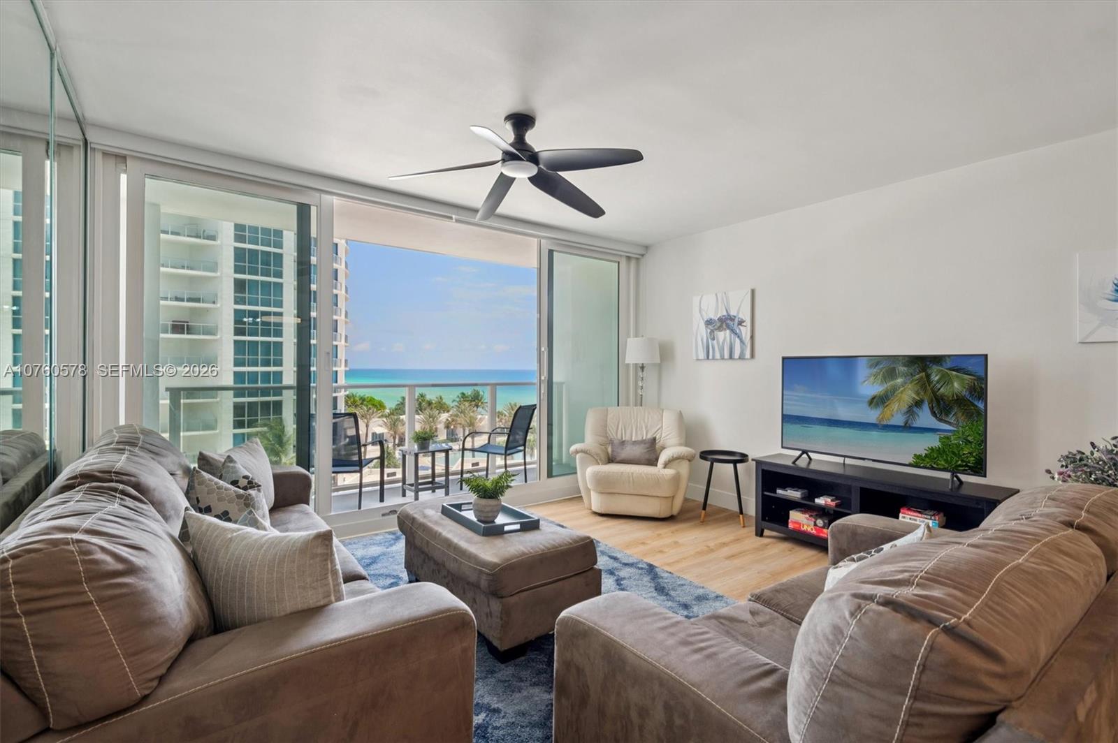 A living room features two brown sofas, an ottoman, and a balcony with ocean views — 3505 S Ocean Dr # 710, Hollywood FL 33019, HOLLYWOOD, FL