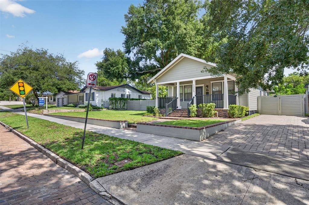 A light green bungalow with a front porch and brick driveway sits on a corner lot — 1225 E AMELIA STREET, ORLANDO, FL