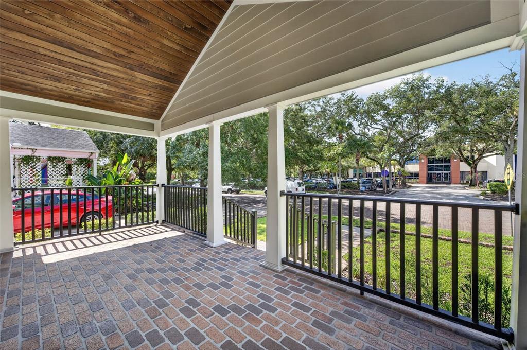 A covered porch with a brick floor, wooden ceiling, and black metal railings overlooking parking — 1225 E AMELIA STREET, ORLANDO, FL