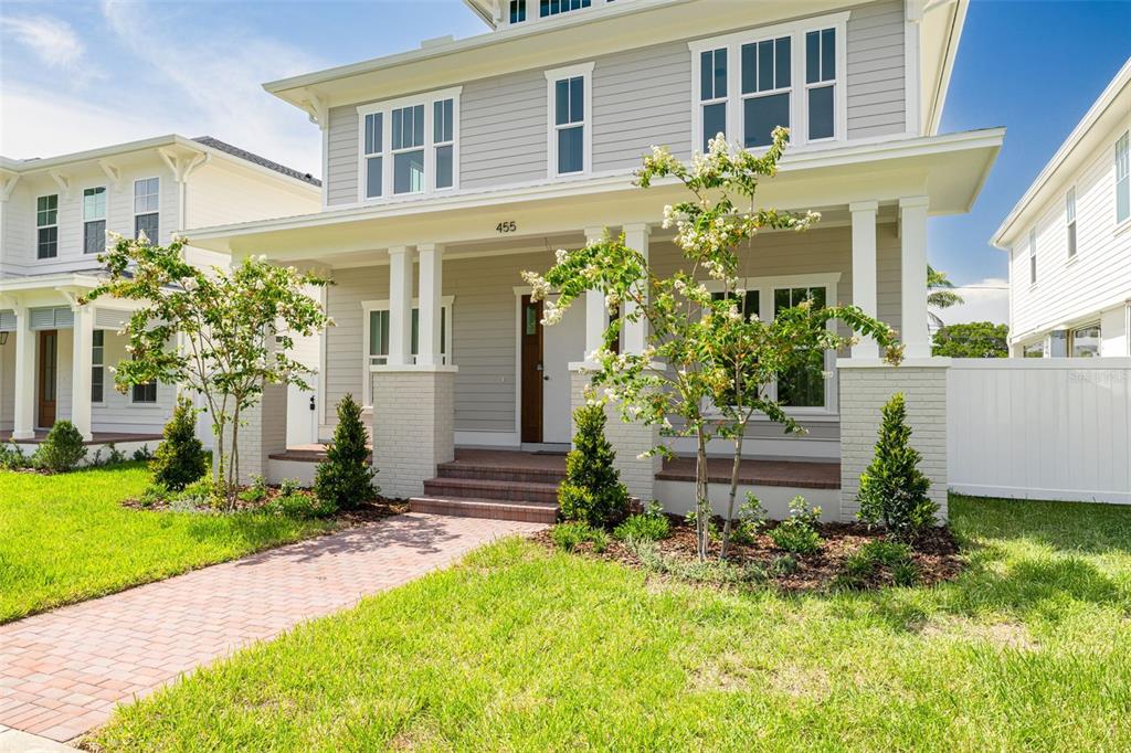 A two-story gray house with a front porch, brick walkway, and manicured landscaping — 455 47TH AVENUE N, ST PETERSBURG, FL