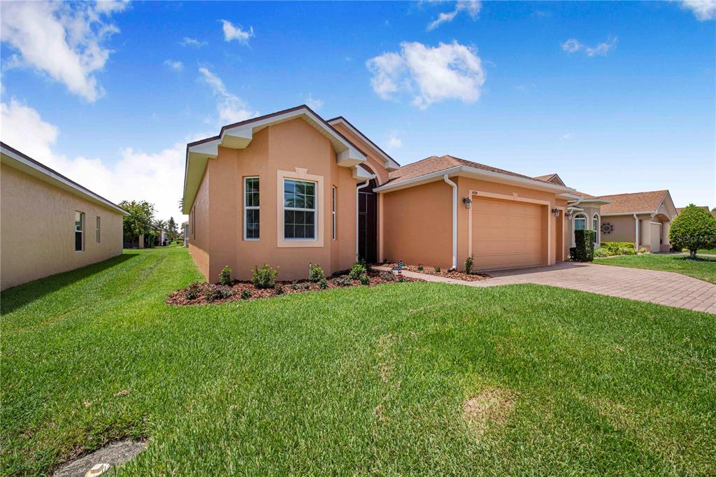 A single-story peach-colored house with a two-car garage and a paved driveway — 4084 STONE CREEK LOOP, LAKE WALES, FL