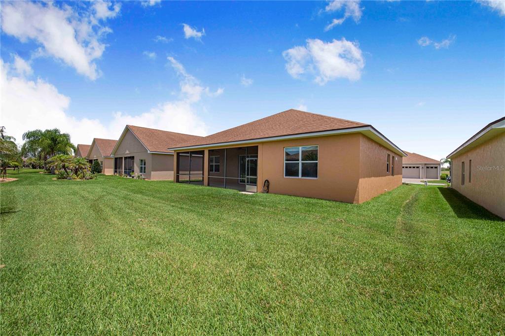 A view of the back exterior of a tan house with a screened-in porch — 4084 STONE CREEK LOOP, LAKE WALES, FL