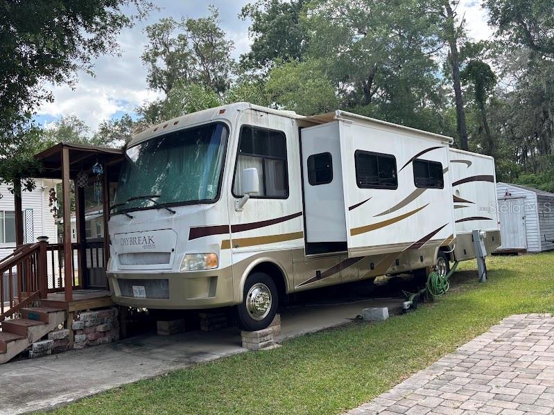A white and tan Daybreak motorhome with a slide-out is parked on a concrete pad — 14427 252ND COURT ROAD NE UNIT 138, FORT MC COY, FL