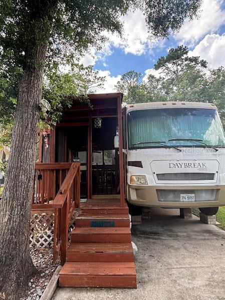 A motorhome is parked next to a wooden deck with stairs leading to a structure — 14427 252ND COURT ROAD NE UNIT 138, FORT MC COY, FL