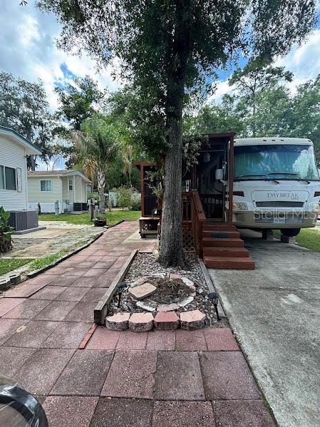 A paved walkway leads to a wooden deck and a parked RV under a tree — 14427 252ND COURT ROAD NE UNIT 138, FORT MC COY, FL