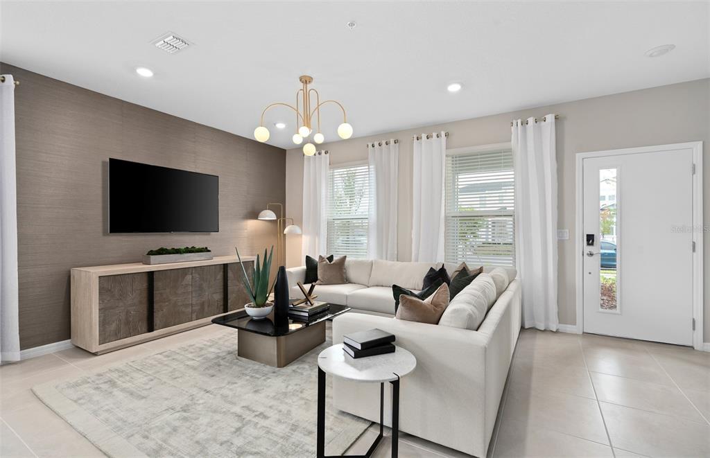 A living room features a textured accent wall, a sectional sofa, and a modern chandelier — 11365 NONA SOUND STREET, ORLANDO, FL
