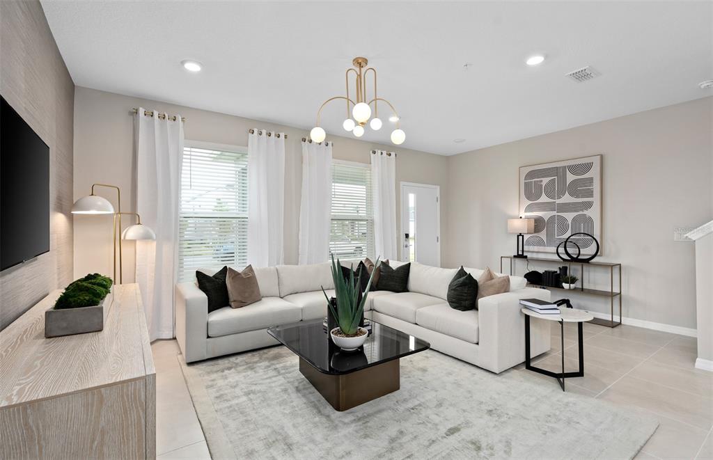 A modern living room features a white sectional sofa, a glass coffee table, and a chandelier — 11365 NONA SOUND STREET, ORLANDO, FL