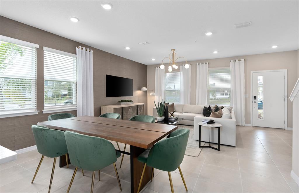 A dining area with a wooden table and green chairs sits beside a living room — 11365 NONA SOUND STREET, ORLANDO, FL