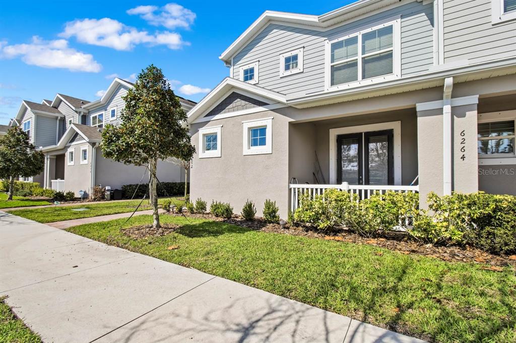 A two-story townhouse with gray siding, a small front porch, and a manicured lawn — 6262 GOLDCOAST AVENUE, APOLLO BEACH, FL