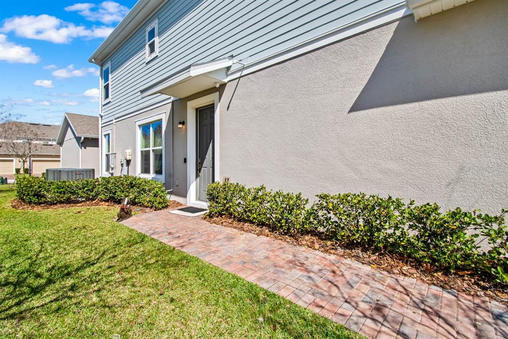 A brick walkway leads to the front entrance of a house with stucco and siding — 6262 GOLDCOAST AVENUE, APOLLO BEACH, FL