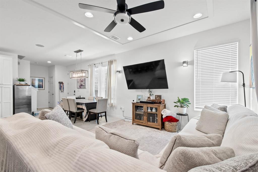 A living room and dining area feature a ceiling fan, wall-mounted television, and neutral furniture — 6262 GOLDCOAST AVENUE, APOLLO BEACH, FL