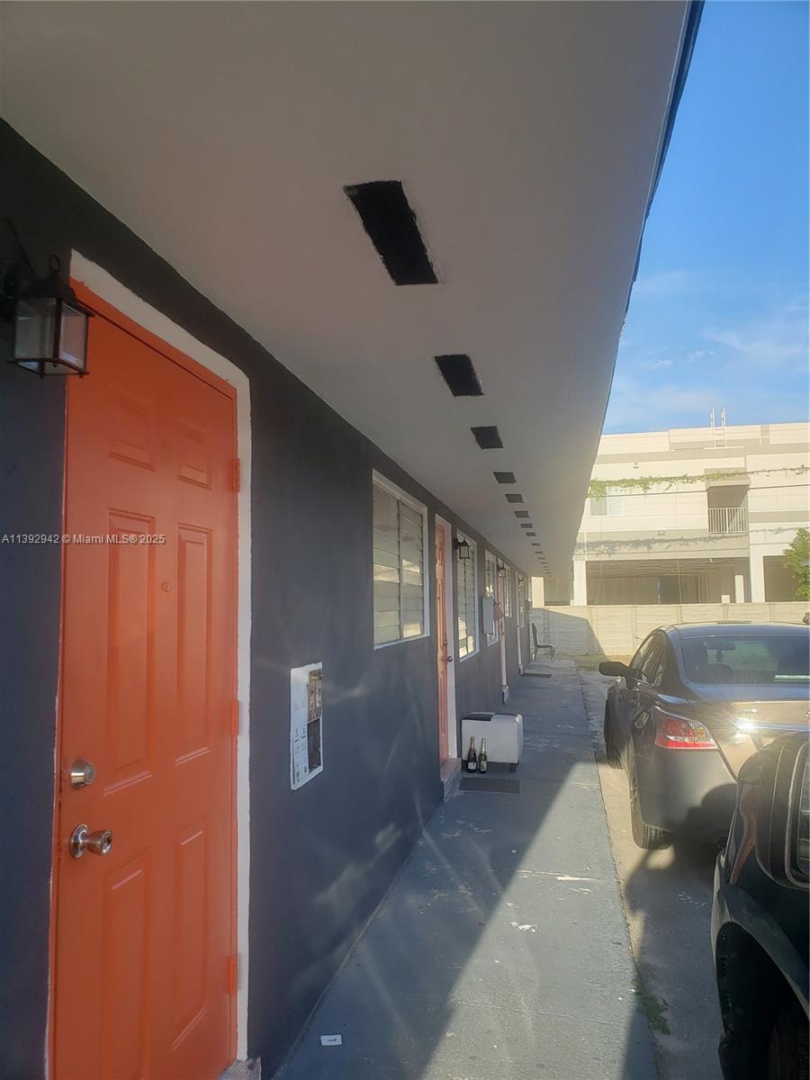 A row of orange doors lines the exterior walkway of a dark-painted building — 2865 NW 22nd Ave, Miami FL 33142, MIAMI, FL