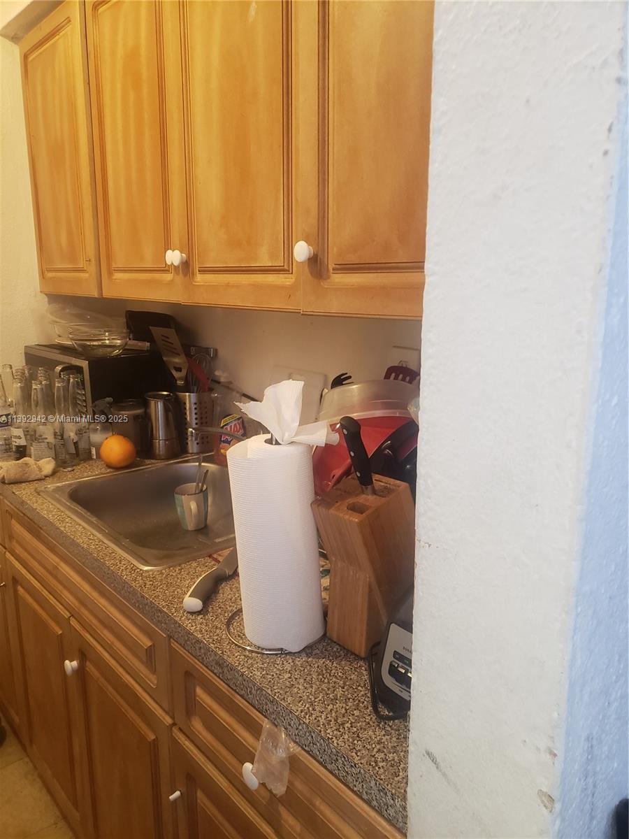 A kitchen features wood cabinets, a stainless steel sink, and a speckled laminate countertop — 2865 NW 22nd Ave, Miami FL 33142, MIAMI, FL