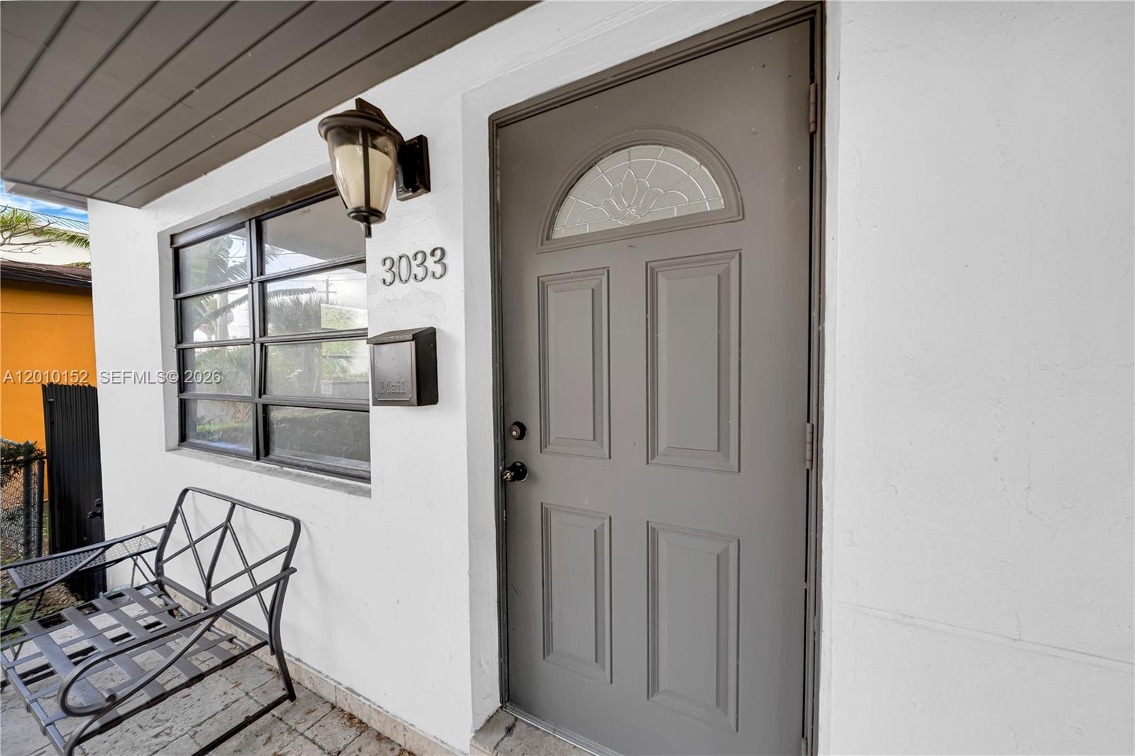 A gray front door with a decorative glass insert sits beside a window and mailbox — 3033 Hibiscus Street, Miami FL 33133, MIAMI, FL