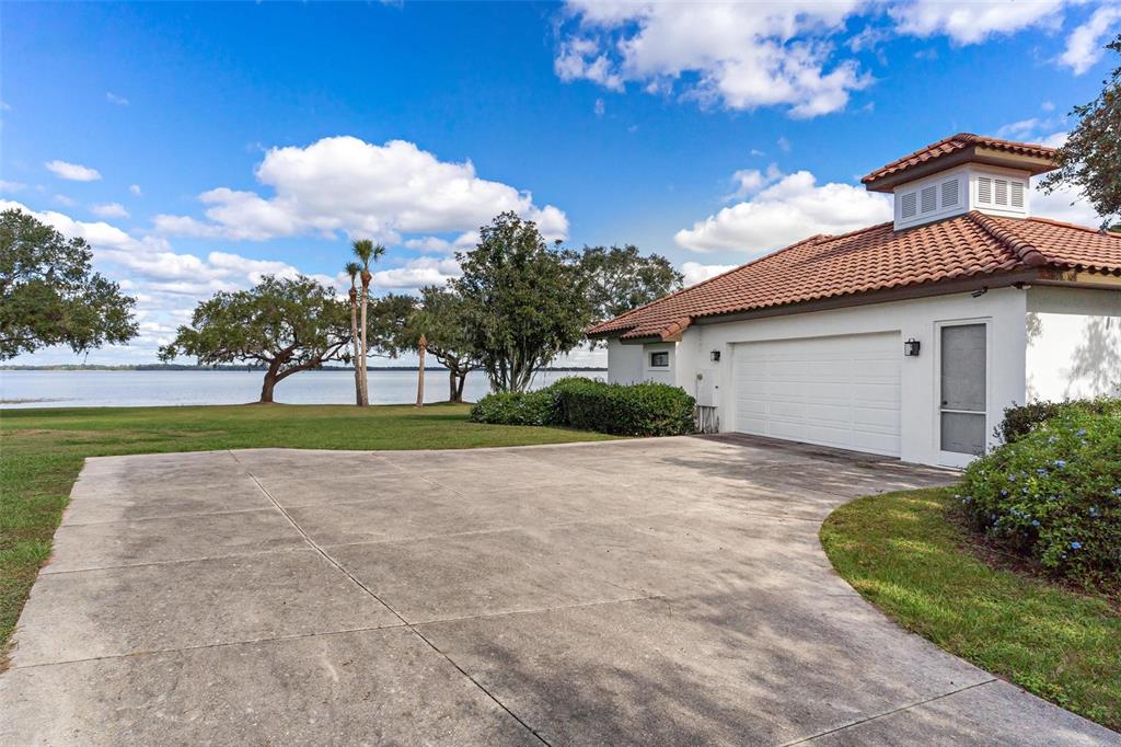 A white garage with a tiled roof sits next to a lake and grassy yard — 38230 YALE CIRCLE, LEESBURG, FL