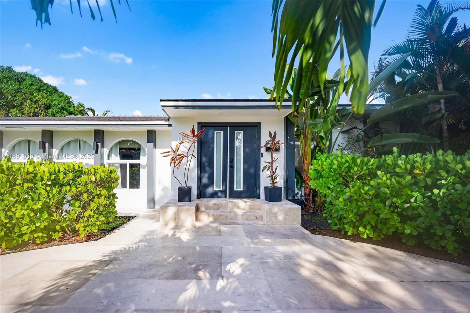 A modern house entrance features double dark doors, stone steps, and lush tropical landscaping — 1651 SW 13th Ave, Miami FL 33145, MIAMI, FL