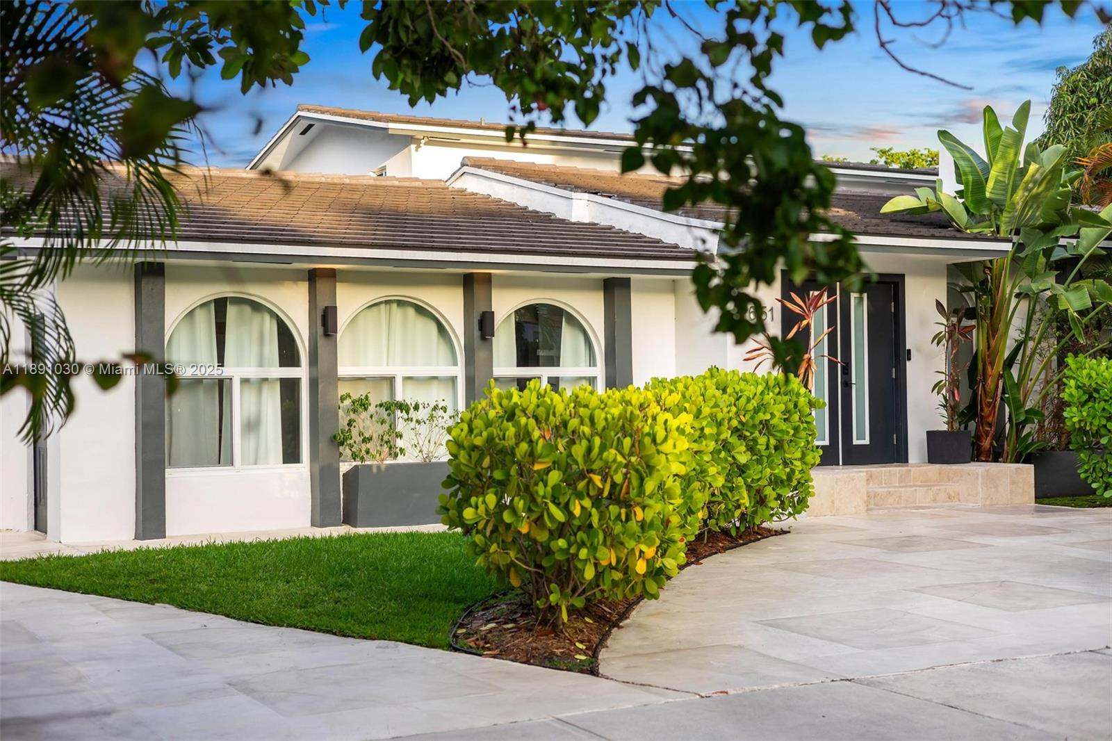 A white house exterior features arched windows, dark trim, and a landscaped front yard — 1651 SW 13th Ave, Miami FL 33145, MIAMI, FL