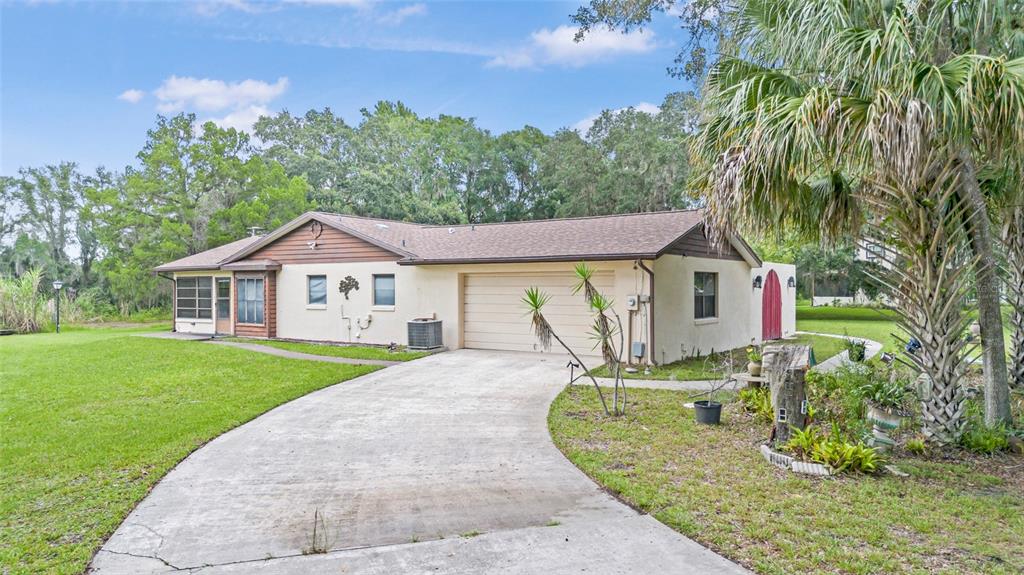 A single-story house with a beige exterior, a two-car garage, and a concrete driveway — 53 N ARCHWOOD DRIVE, INVERNESS, FL