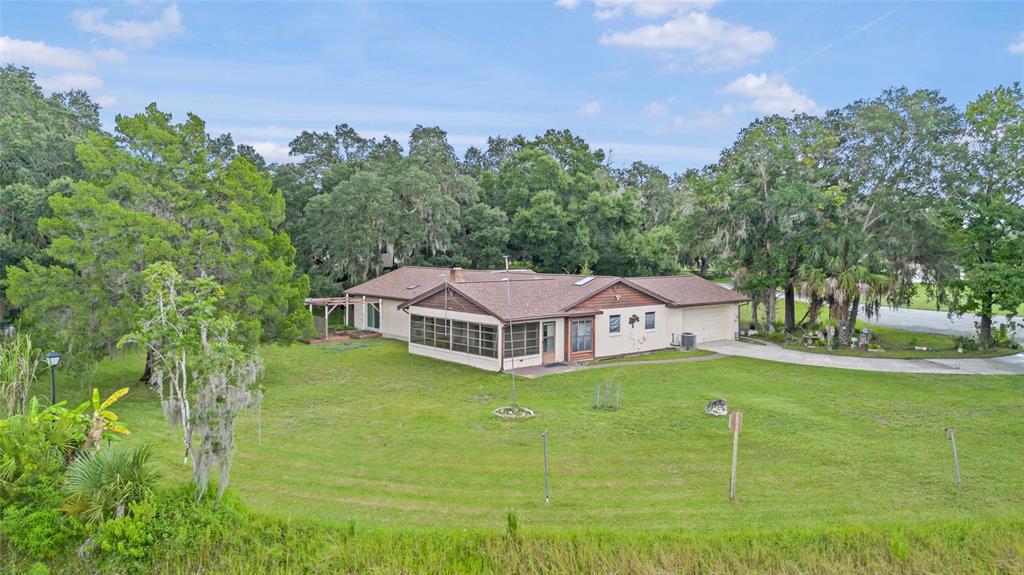 An exterior view of a single-story house with a screened porch and a large lawn — 53 N ARCHWOOD DRIVE, INVERNESS, FL