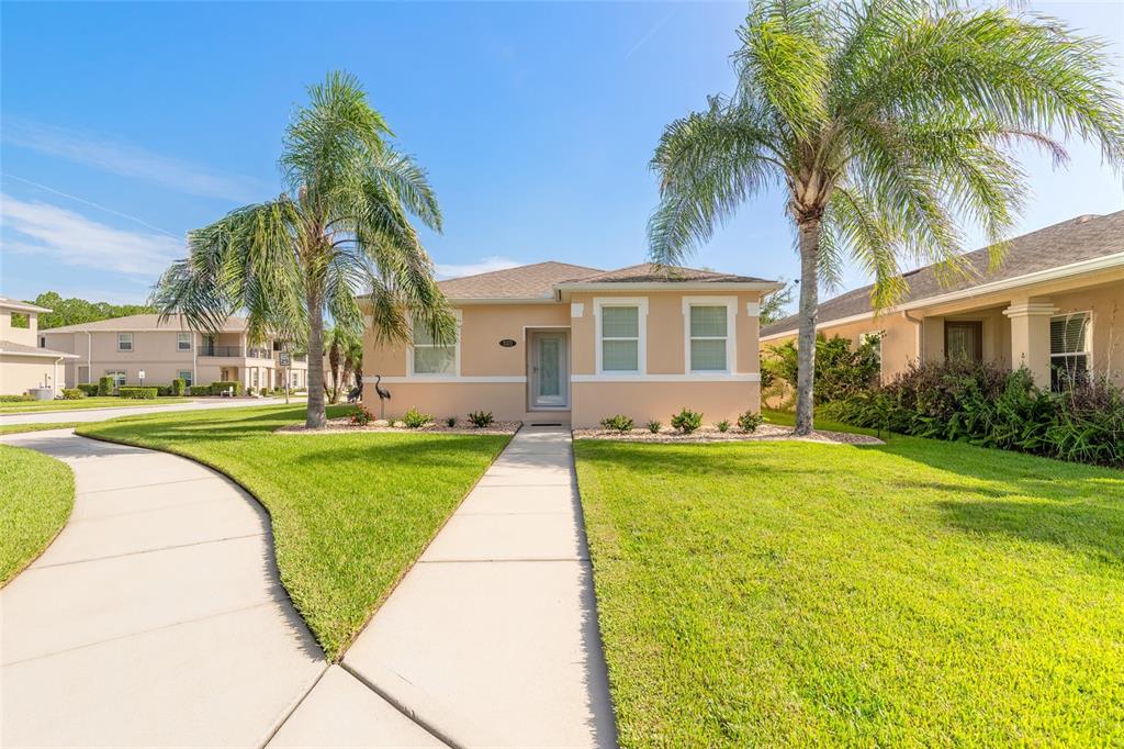 A single-story tan house with a front walkway and two palm trees on the lawn — 3371 MEDICI BOULEVARD, NEW SMYRNA BEACH, FL