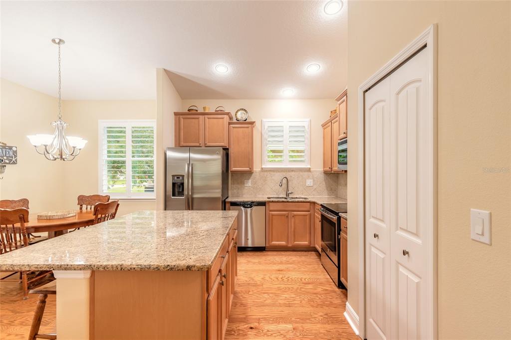 A kitchen with wood cabinets, granite countertops, stainless steel appliances, and an island — 3371 MEDICI BOULEVARD, NEW SMYRNA BEACH, FL