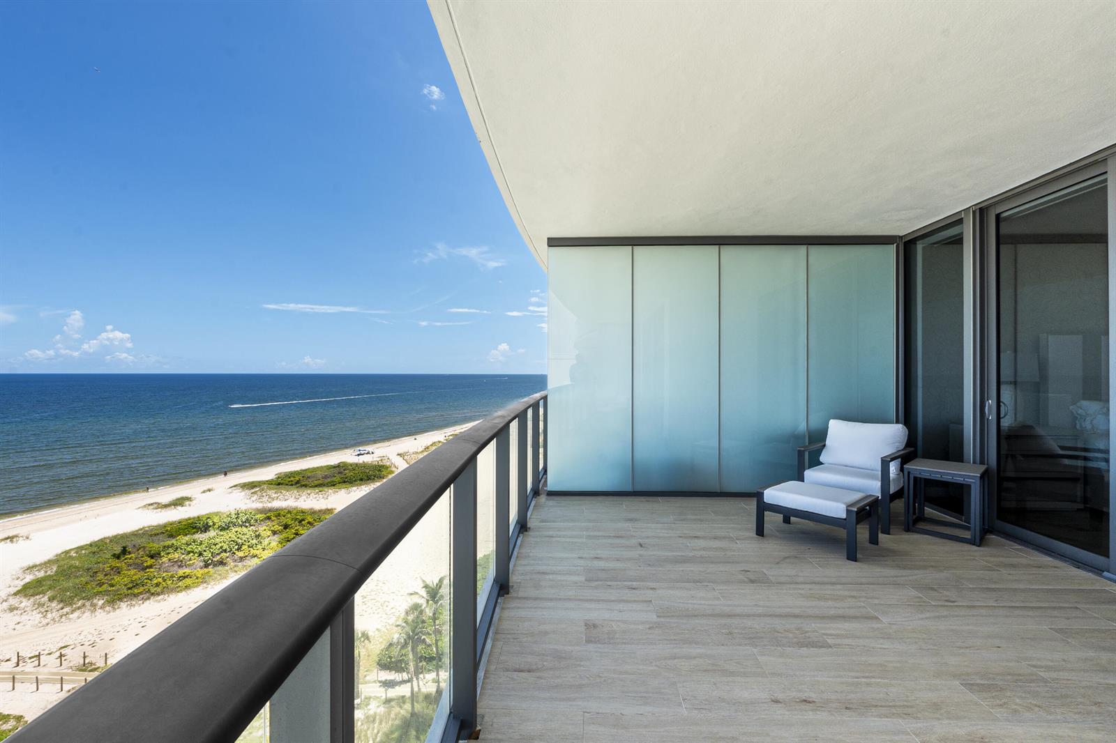 A balcony with wood-look tile flooring, a glass railing, and a view of the ocean — 1116 N Ocean Boulevard # 904, Pompano Beach FL 33062, POMPANO BEACH, FL