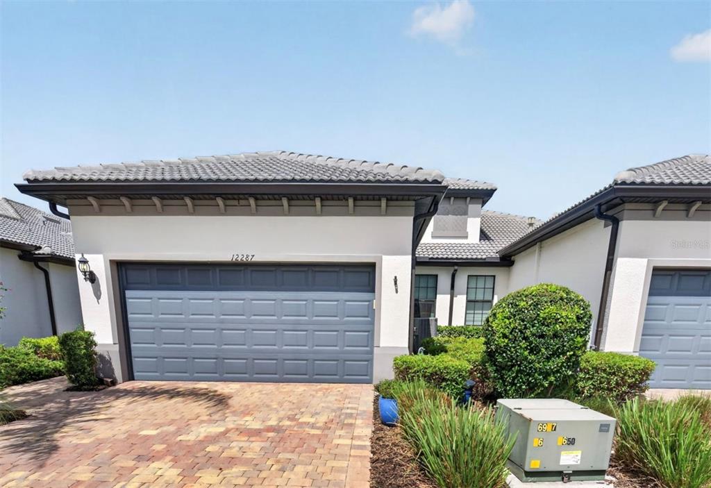A view of a house exterior featuring a two-car garage and a paved driveway — 12287 MYRTLE BAY COURT, SARASOTA, FL