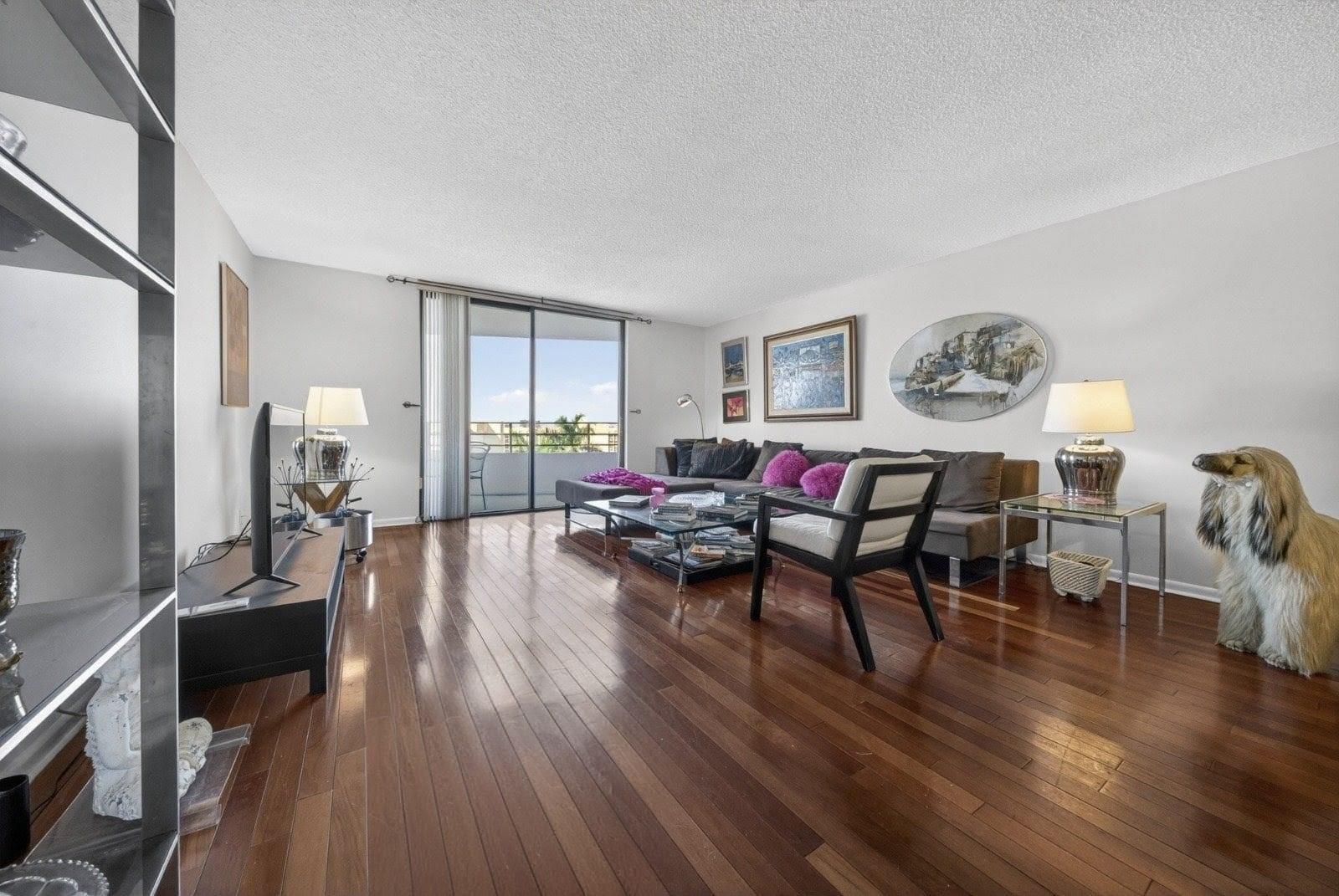 A living room with hardwood floors, a sectional sofa, and a sliding door to a balcony — 600 Three Islands Boulevard # 406, Hallandale Beach FL 33009, HALLANDALE BEACH, FL
