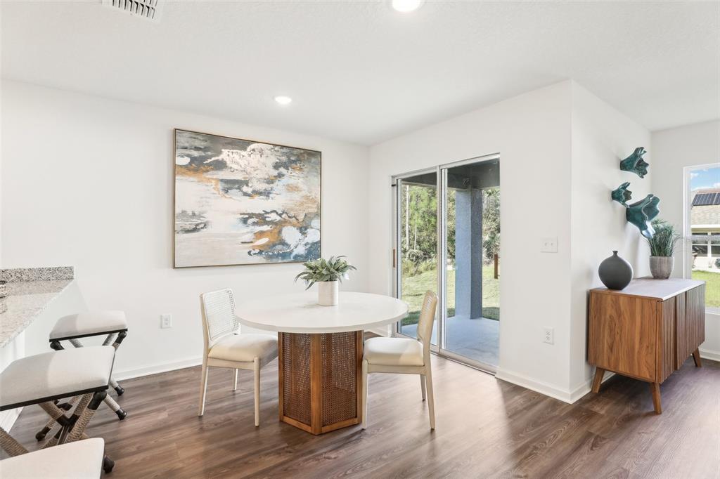 A dining area features a round table, two chairs, a sideboard, and sliding glass doors — 7100 PLUMOSA LANE, FORT PIERCE, FL