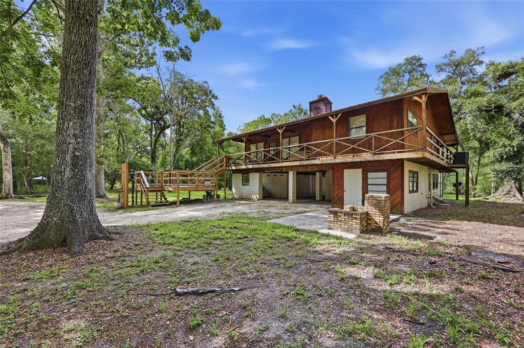 A two-story wooden house with a wrap-around deck stands in a wooded yard — 470 SW SANTA FE DRIVE, FORT WHITE, FL