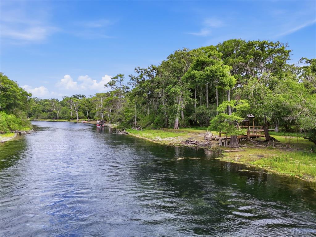A river flows past a grassy bank with trees and a small wooden gazebo — 470 SW SANTA FE DRIVE, FORT WHITE, FL