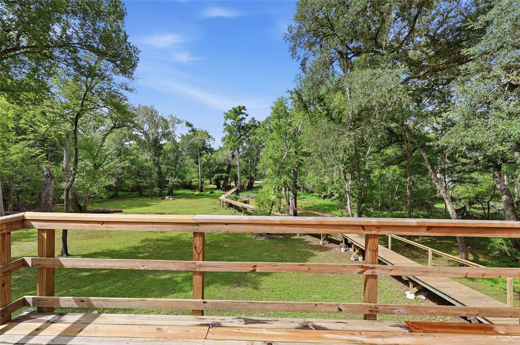 A wooden deck overlooks a grassy yard with a long boardwalk winding through the trees — 470 SW SANTA FE DRIVE, FORT WHITE, FL
