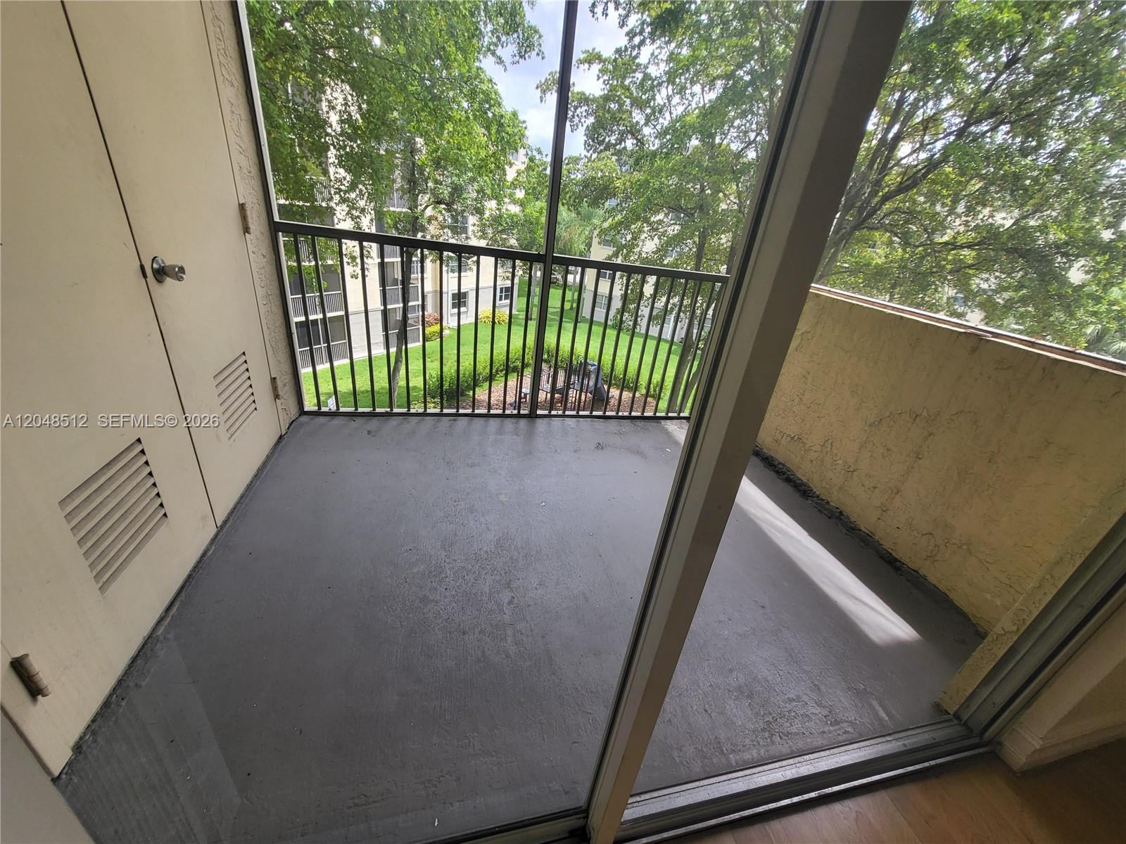 A screened-in balcony features a gray concrete floor, a storage closet, and metal railings — 8225 Lake Dr # 405, Doral FL 33166, DORAL, FL