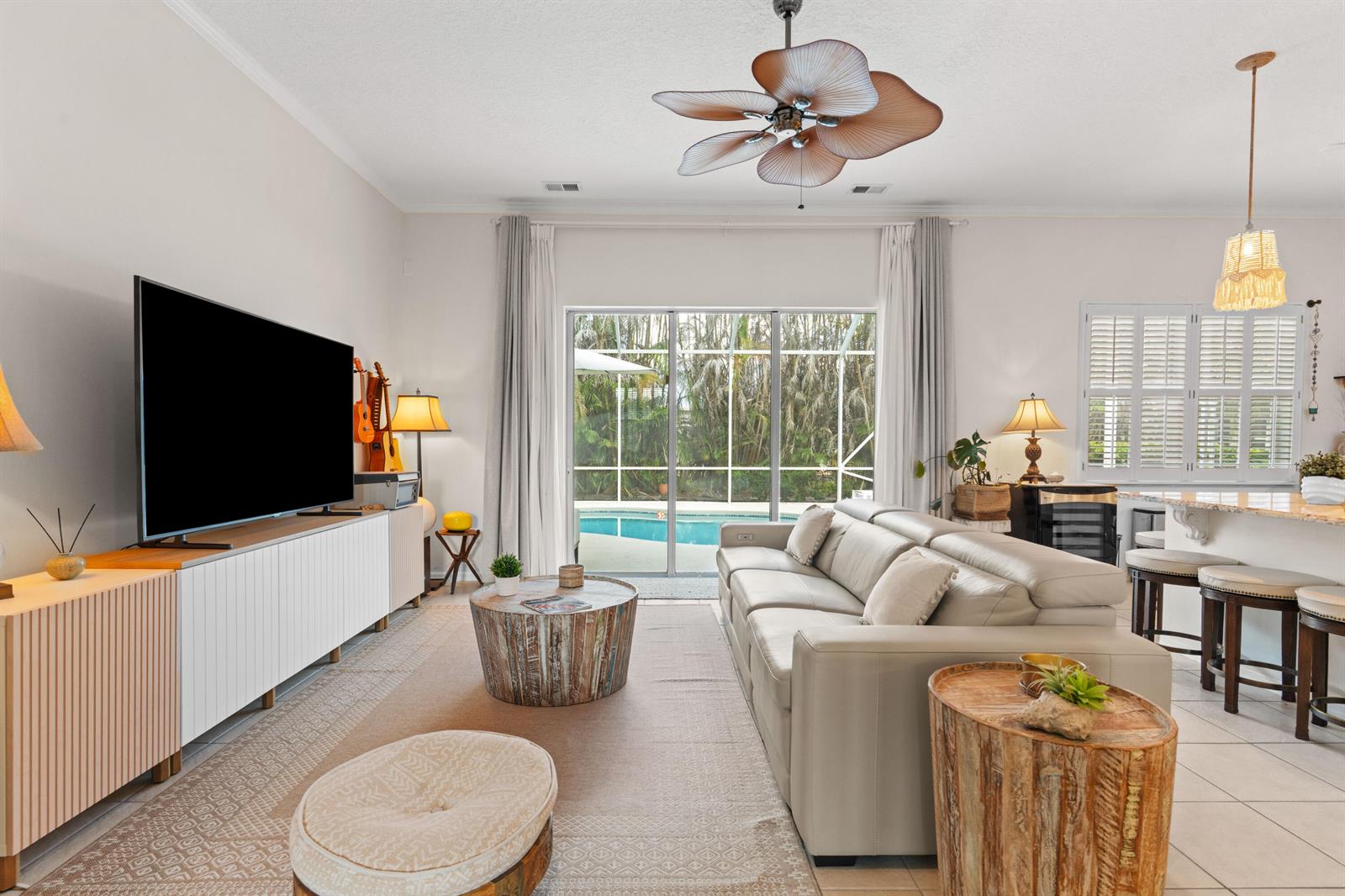 A living room features a white sofa, a television, a coffee table, and pool views — VERO BEACH, FL