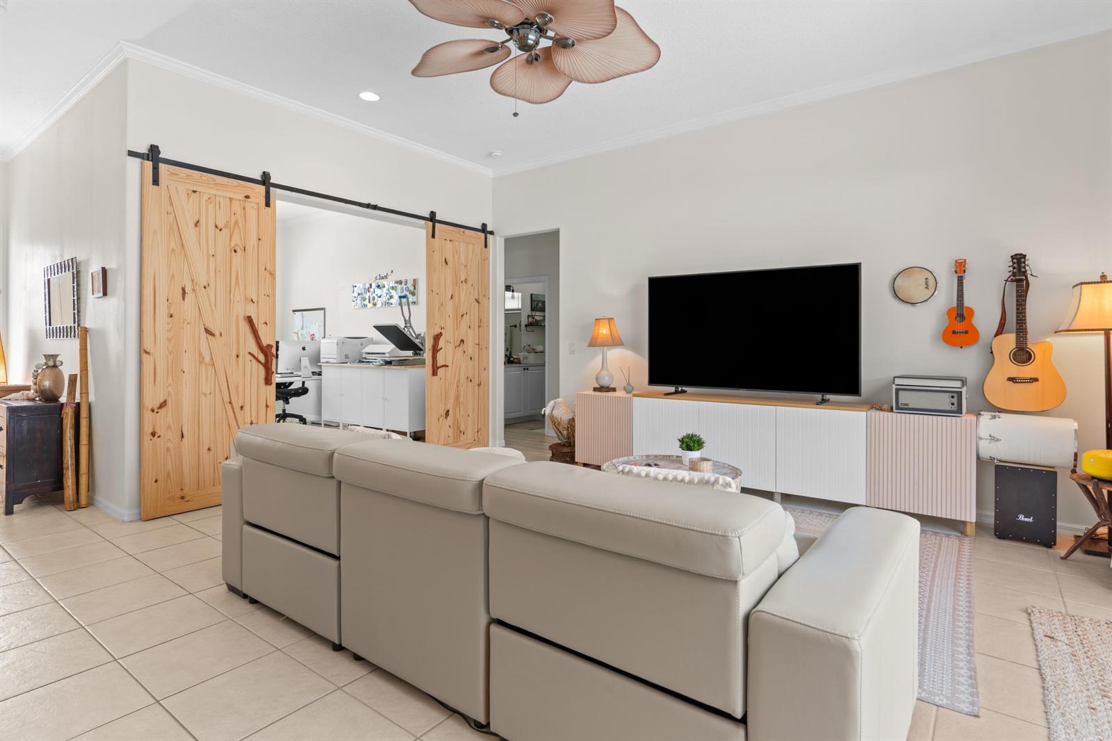 A living room features a light-colored sectional sofa, a television on a cabinet, and barn doors — VERO BEACH, FL