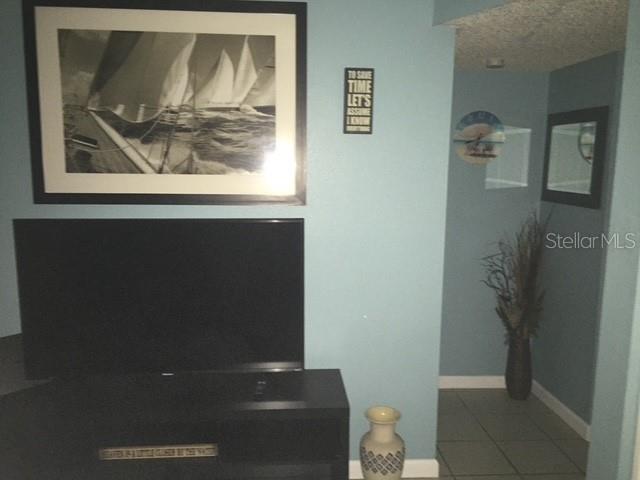 A television sits on a black stand below a framed sailboat print on a blue wall — 7710 BAYSHORE DRIVE UNIT 2, TREASURE ISLAND, FL