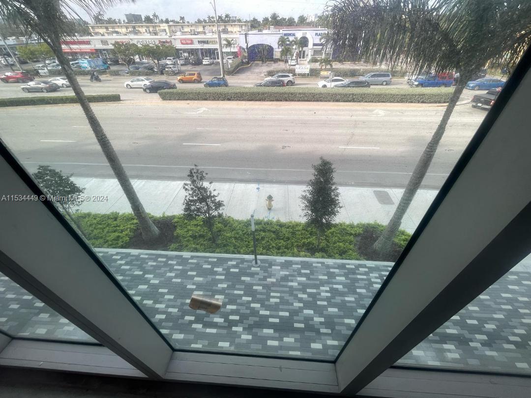 A view from a window looking out over a multi-lane road and a shopping plaza — 1006 E HALLANDALE BEACH BLVD # 206, Hallandale Beach FL 33009, HALLANDALE BEACH, FL