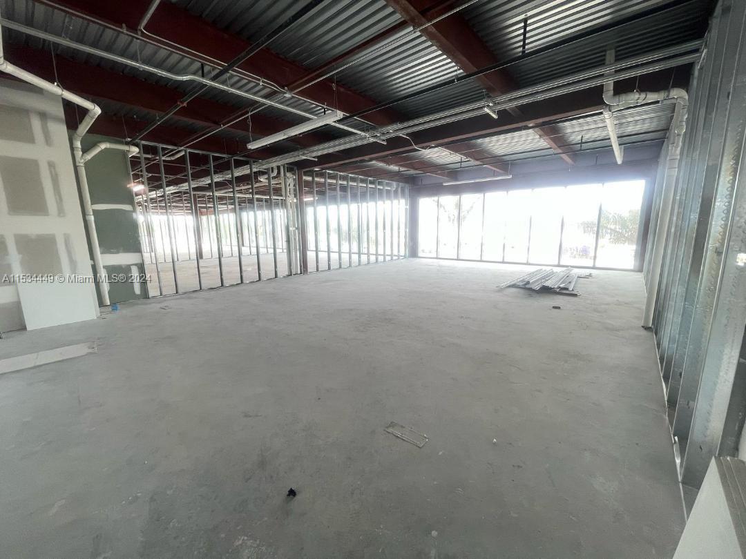 An unfinished commercial interior features exposed ceiling beams, metal wall studs, and large windows — 1006 E HALLANDALE BEACH BLVD # 206, Hallandale Beach FL 33009, HALLANDALE BEACH, FL