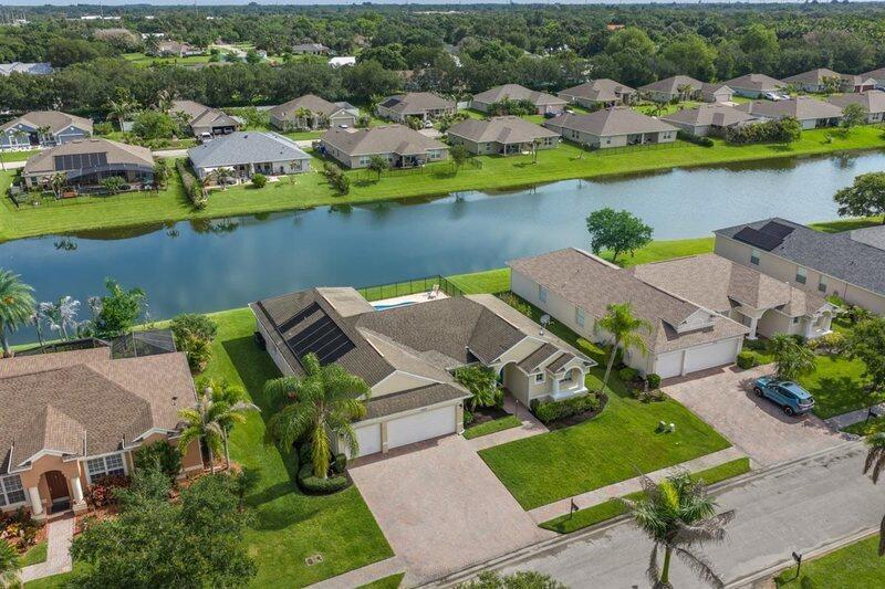 An aerial view shows suburban houses with swimming pools and solar panels along a canal — VERO BEACH, FL