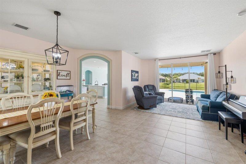 A dining area and living room with tile floors, a sliding glass door, and pool view — VERO BEACH, FL