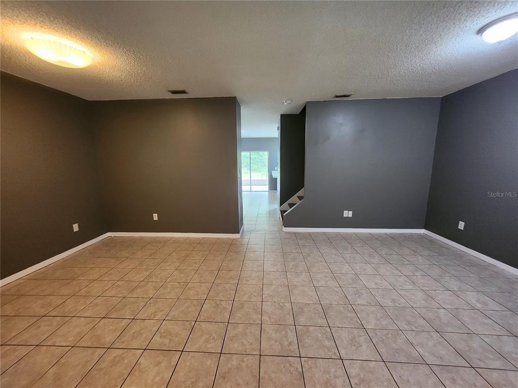 A room with dark gray walls, tiled flooring, and a view into an adjacent space — 30151 BARNABY LANE, WESLEY CHAPEL, FL