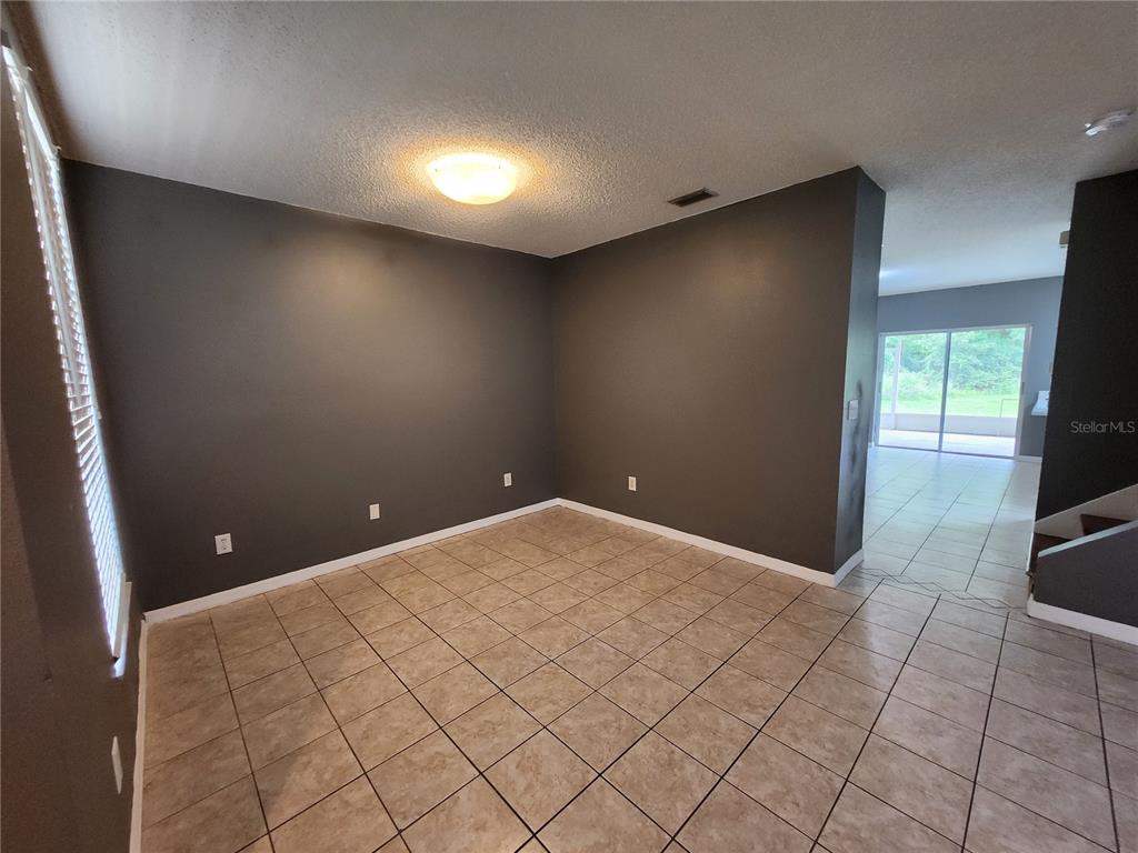 An empty room with dark gray walls, tile flooring, and a ceiling light fixture — 30151 BARNABY LANE, WESLEY CHAPEL, FL
