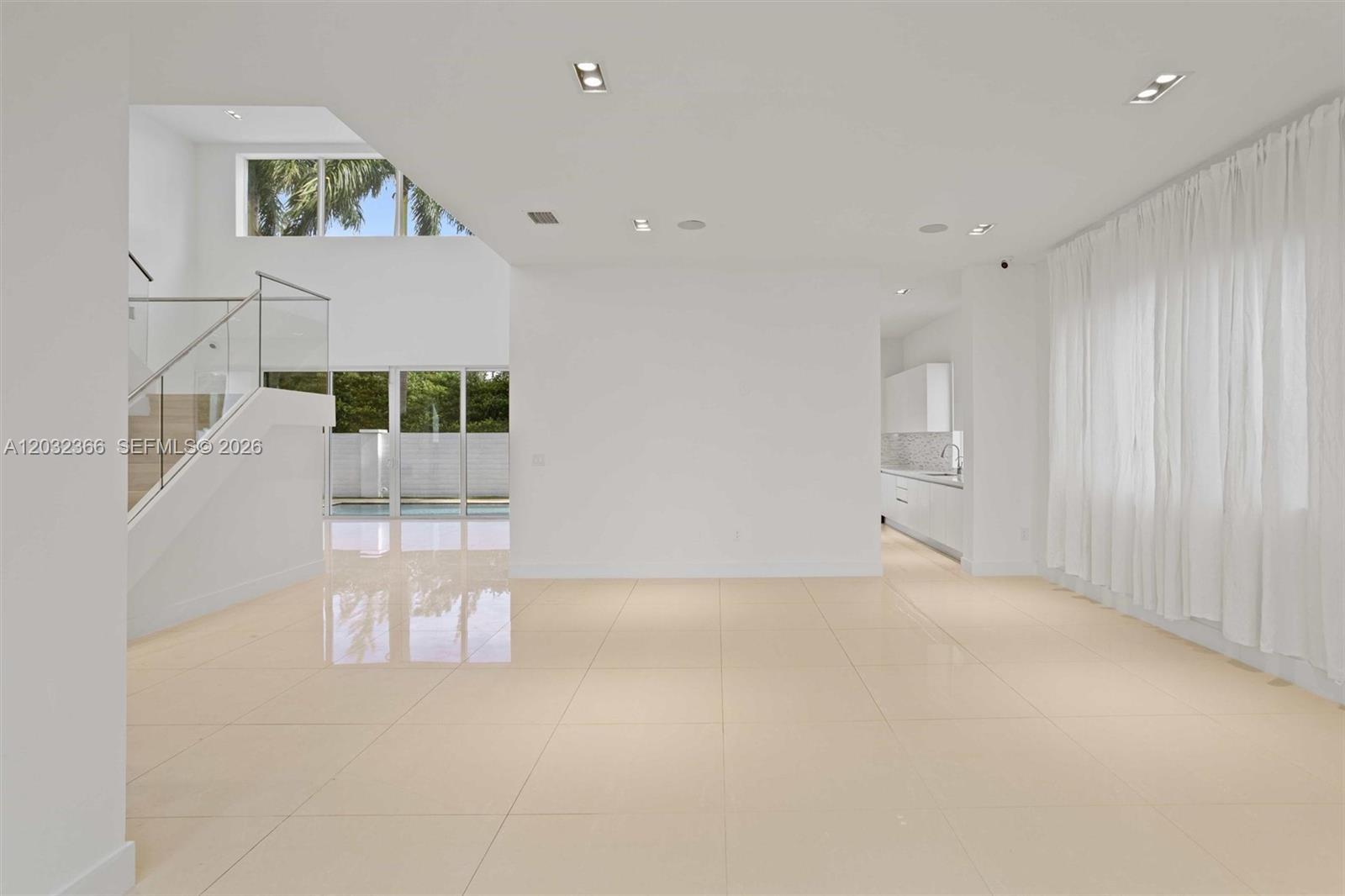 A bright, open-plan living area features white walls, large tile flooring, and a glass staircase — 10296 NW 74th Terrace, Doral FL 33178, DORAL, FL